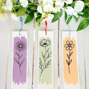 May include: Three rectangular paper bookmarks featuring black line art of flowers centered over vertical brushstrokes of color. The left bookmark has a purple stroke, the center a light green, and the right a peach stroke, each with a colored tassel.