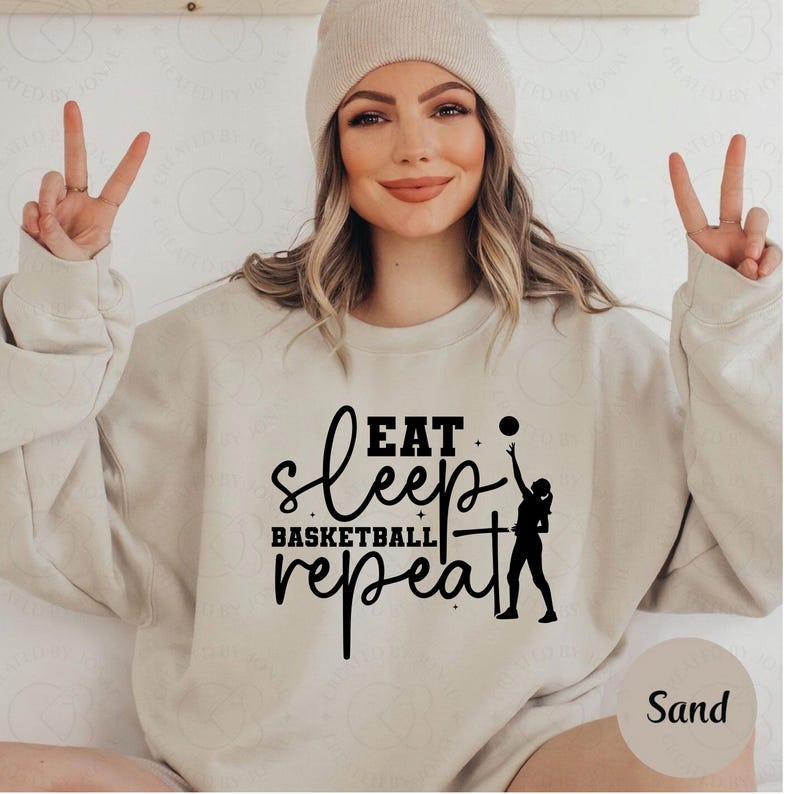 Pu&ograve; includere: Felpa color sabbia con la scritta "Eat Sleep Basketball Repeat" in nero. Il design include la silhouette di una persona che tira a canestro. La felpa &egrave; uno stile casual e confortevole.