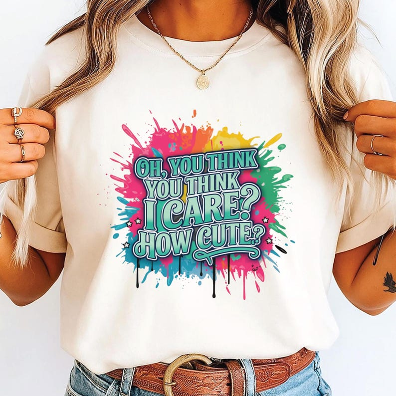 K&ouml;nnte beinhalten: Cremefarbenes T-Shirt mit einem farbenfrohen Grafikdesign. Der Aufdruck zeigt den Text "OH, YOU THINK YOU THINK I CARE? HOW CUTE?" in Pink, Blau, Gelb und Gr&uuml;n, mit einem Tropfeffekt. Das Shirt hat einen Rundhalsausschnitt und kurze &Auml;rmel.
