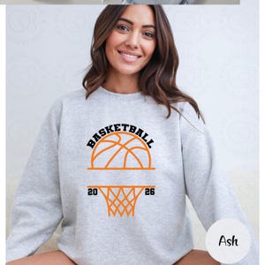 Pu&ograve; includere: Felpa grigio chiaro con grafica di basket. La grafica include la parola "BASKETBALL" sopra un disegno di pallone da basket, con i numeri "20" e "26" ai lati di un canestro. La felpa &egrave; realizzata in materiale morbido.