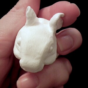 K&ouml;nnte beinhalten: Wei&szlig;e Keramikskulptur eines kleinen Tieres mit gro&szlig;en Ohren, das einem Kaninchen oder einem Eichh&ouml;rnchen &auml;hnelt. Die Skulptur ist detailliert mit strukturiertem Fell und einer kleinen Nase.