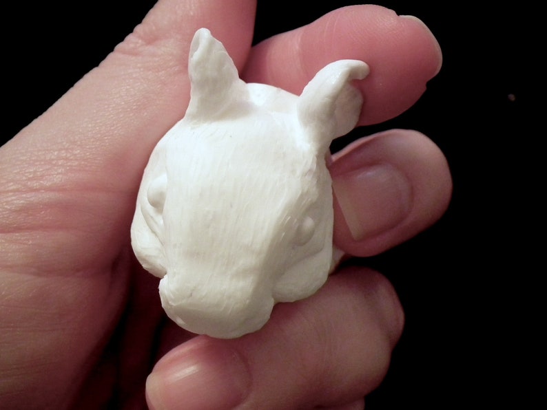 K&ouml;nnte beinhalten: Wei&szlig;e Keramikskulptur eines kleinen Tieres mit gro&szlig;en Ohren, das einem Kaninchen oder einem Eichh&ouml;rnchen &auml;hnelt. Die Skulptur ist detailliert mit strukturiertem Fell und einer kleinen Nase.