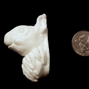 K&ouml;nnte beinhalten: Wei&szlig;e Keramikskulptur eines Eichh&ouml;rnchenkopfes und Vorderpfoten, das Eichh&ouml;rnchen schaut nach rechts. Die Skulptur ist etwa so gro&szlig; wie eine deutsche 2-Euro-M&uuml;nze.