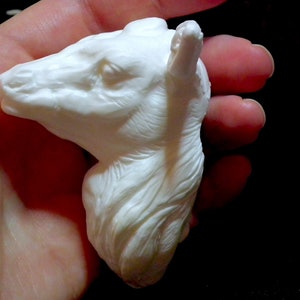 Op de afbeelding: Witte keramische sculptuur van een lamahoofd met gedetailleerde vacht en gezichtskenmerken.