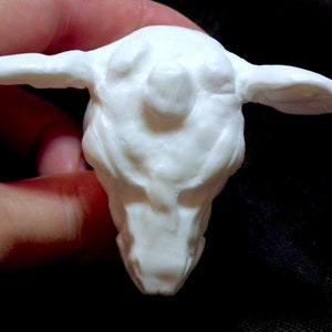 Op de afbeelding: Witte keramische sculptuur van een schepsel met een groot hoofd en kleine oren. De sculptuur is gedetailleerd met textuurkenmerken en een ronde, bolle neus.