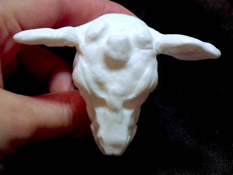 Op de afbeelding: Witte keramische sculptuur van een schepsel met een groot hoofd en kleine oren. De sculptuur is gedetailleerd met textuurkenmerken en een ronde, bolle neus.