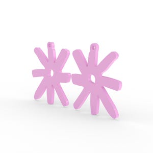 May include: Two light pink, flower-shaped earrings. Each earring has a central hole and eight petals. The earrings are made of a solid material and have a small loop at the top for hanging. The background is white.