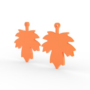 K&ouml;nnte beinhalten: Zwei orangefarbene Ahornblatt-Anh&auml;nger. Jeder Anh&auml;nger hat oben eine kleine Schlaufe zum Aufh&auml;ngen. Die Bl&auml;tter haben detaillierte Kanten und ein dreidimensionales Aussehen, was darauf hindeutet, dass sie aus einem festen Material bestehen.