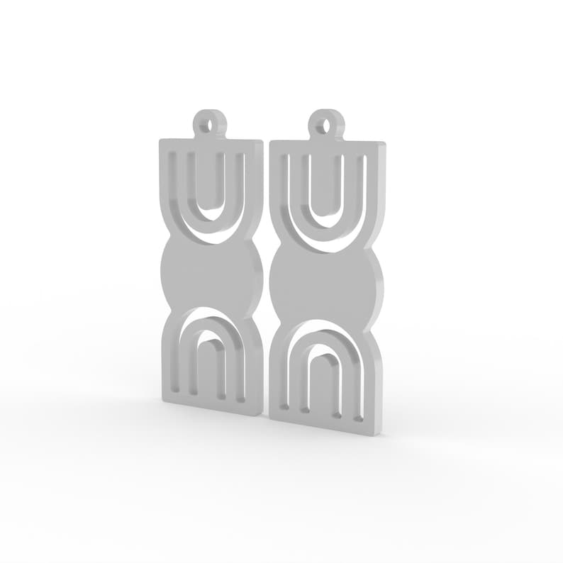 May include: A pair of gray geometric earrings. Each earring features a series of connected shapes: a rounded top, a circle, and a curved bottom. The earrings have a minimalist design and a small loop at the top for hanging.