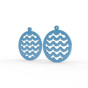 Puede incluir: Dos colgantes circulares de color azul claro con un patr&oacute;n de ondas recortado. Cada colgante tiene un peque&ntilde;o lazo circular en la parte superior para su fijaci&oacute;n. El dise&ntilde;o consiste en un anillo exterior s&oacute;lido con l&iacute;neas onduladas.