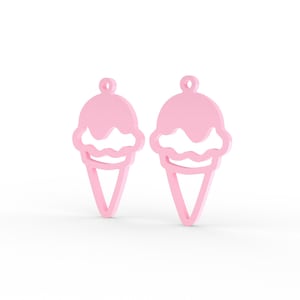 Puede incluir: Un par de dijes de cono de helado de color rosa claro con un dise&ntilde;o recortado. Cada dije tiene una forma de bola redondeada en la parte superior con un borde ondulado y una base de cono triangular, con un peque&ntilde;o lazo circular en la parte superior.