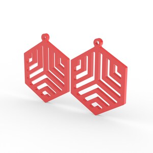 May include: Two red geometric earrings with a hexagonal shape and a cut-out design. Each earring has a small loop at the top for hanging. The earrings are displayed against a white background.