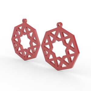 May include: Two red geometric earrings with a star-shaped cutout in the center. The earrings have a hexagonal shape with a small loop at the top for hanging. The design features a series of triangles forming the outer shape.