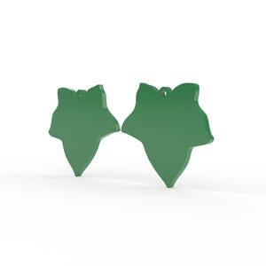K&ouml;nnte beinhalten: Zwei gr&uuml;ne, blattf&ouml;rmige Ornamente. Jedes Ornament hat oben ein Loch zum Aufh&auml;ngen. Die Bl&auml;tter haben eine einfarbige, gl&auml;nzende gr&uuml;ne Farbe und werden vor einem wei&szlig;en Hintergrund dargestellt. Die Ornamente dienen wahrscheinlich der Dekoration.