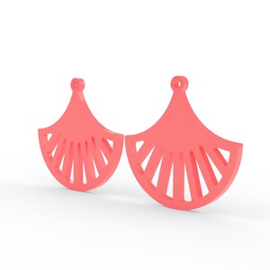 May include: A pair of coral-colored earrings. Each earring has a fan-like shape with a series of vertical cutouts. The earrings have a small loop at the top for hanging. The background is plain white.