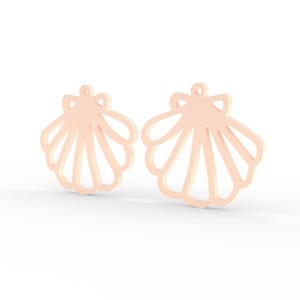 Puede incluir: Dos dijes en forma de concha de color melocot&oacute;n p&aacute;lido con un dise&ntilde;o recortado. Cada dije presenta un borde festoneado y un peque&ntilde;o lazo circular en la parte superior para su fijaci&oacute;n. Los art&iacute;culos tienen un acabado mate, liso y sim&eacute;trico.