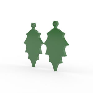 K&ouml;nnte beinhalten: Zwei gr&uuml;ne Stechpalmenblatt-Ornamente mit einer Schlaufe zum Aufh&auml;ngen. Die Bl&auml;tter haben eine klassische Stechpalmenform mit spitzen Kanten. Die Ornamente sind vor einem wei&szlig;en Hintergrund platziert.