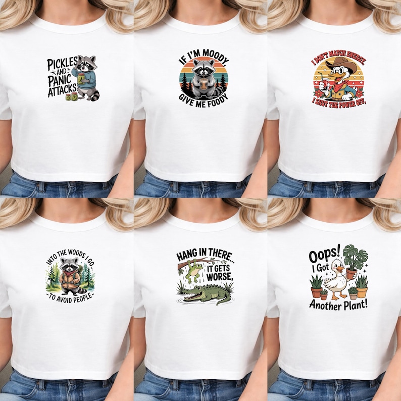 May include: A collection of six white t-shirts featuring various graphic prints: a raccoon with pickles, a raccoon with food, a duck in a cowboy hat, a raccoon in the woods, a frog and alligator, and a duck holding a potted plant with text.