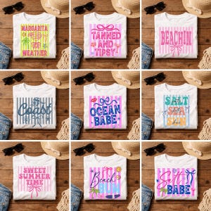 Op de afbeelding: Witte T-shirts met zomerse afbeeldingen en tekst. Ontwerpen omvatten "Margarita Weather", "Tanned and Tipsy", "Beachin'", "Coast", "Ocean Babe", "Salt Sea Shine", "Sweet Summer Time", "Beach Bum" en "Salt Babe".