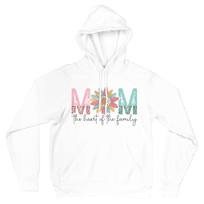 May include: White hoodie with the word "MOM" in pink, teal, and floral-patterned letters, with a sunflower in the center. Below the word "MOM" is the phrase "the heart of the family" in a black script font.
