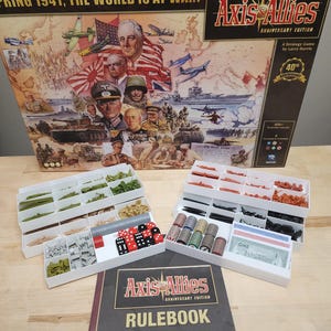 May include: Axis & Allies Anniversary Edition board game box with game pieces and rulebook. The box features a collage of historical figures and military vehicles. Includes dice, game pieces, and play money. The rulebook is visible.