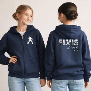 Pu&ograve; includere: Una felpa con cappuccio e zip blu navy con la silhouette bianca di un cantante sul petto a sinistra. Il retro mostra la scritta ELVIS in un carattere bianco a pois con la firma Elvis Presley scritta in bianco in corsivo sotto il nome.