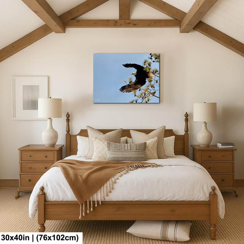 May include: A framed canvas print of an eagle in flight against a blue sky, mounted above a wooden bed. The print measures 76x102cm. The bedroom features a wooden bed frame, nightstands, and a neutral color palette.
