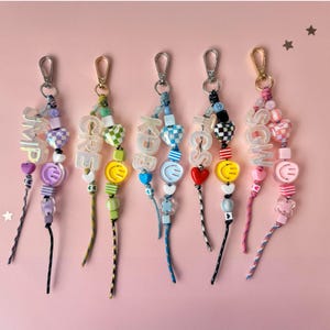 Colgante para bolso con inicial personalizada, letras holográficas y paracord con cuentas, con cierre metálico giratorio.