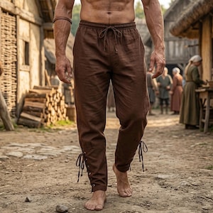 May include: Brown linen pants with a drawstring waist and lace-up details at the ankles. The pants are a solid color and appear to be made of a lightweight fabric. The pants are part of a historical or costume-themed outfit.