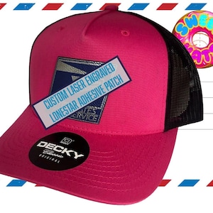 May include: A hot pink trucker hat with a black mesh back. The hat features a white patch with blue text that reads "CUSTOM LASER ENGRAVED LONESTAR ADHESIVE PATCH". A USPS logo is on the patch. A cartoon donut is in the background.