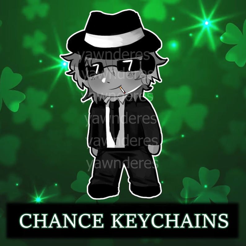 May include: A cartoon character keychain in a black suit, fedora, and sunglasses, with a cigarette in their mouth. The background is green with shamrocks and text that reads "CHANCE KEYCHAINS".
