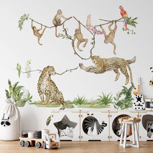 Può includere: Decalcomanie murali ad acquerello a tema giungla con scimmie, leopardi, pappagalli e vegetazione lussureggiante. Il design include una disposizione giocosa di animali e piante, creando un'atmosfera vibrante e stravagante per la cameretta di un bambino.