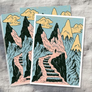 May include: A rectangular art print featuring a stylized mountain landscape with a winding stone staircase leading upward. The scene includes black, pink, and pale yellow peaks against a light blue sky with yellow clouds and a small figure.