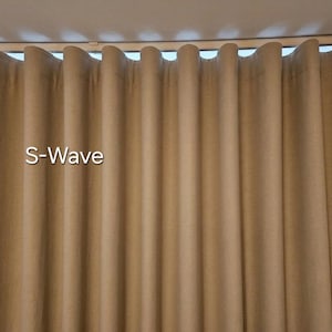 Puede incluir: Una cortina de color tostado con un patr&oacute;n de pliegues en forma de S-Wave que cuelga de un sistema de rieles. La tela muestra una textura uniforme y suave con pliegues verticales que crean un efecto de onda repetitivo en todo el ancho.