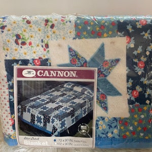 May include: A white and blue patchwork blanket with a star pattern. The blanket is packaged and labeled "CANNON Star Patch Blanket" with sizes 72 x 90 in. and 102 x 90 in.