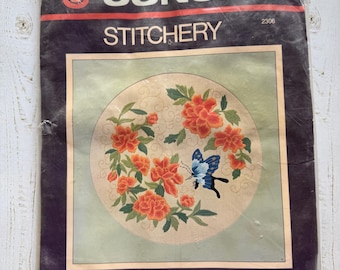 Peut inclure: Un kit de broderie Sunset Stitchery avec un motif de pivoines chinoises et un papillon bleu. Le kit est conçu par Diane Brakefield et convient à un cadre de 40,6 cm x 40,6 cm.