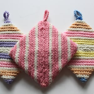 Peut inclure: Trois maniques en crochet en forme de losange avec des boucles de suspension. Les maniques sont rayées de rose et blanc, de violet et blanc, et de jaune et blanc.