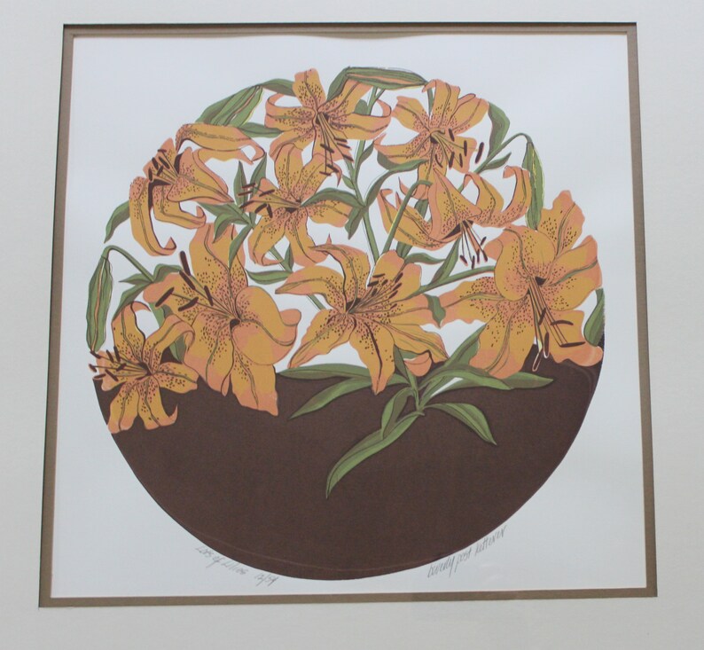 May include: A framed print of a circular design featuring a cluster of orange lilies with brown stems and leaves on a brown background. The print is signed "Dorothy West Halloran".