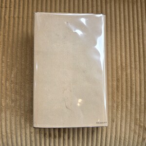May include: A rectangular book encased in transparent plastic. The book features a pale beige cover with a lightly textured finish. The number "394-60418-0" is visible in the bottom right corner.