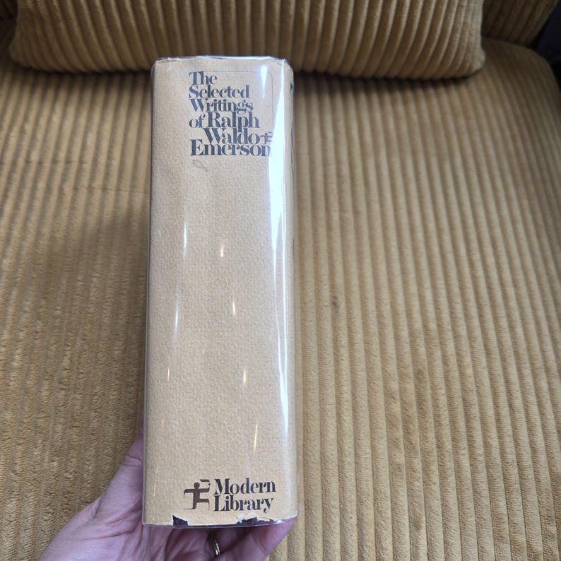 May include: A hardback book titled "The Selected Writings of Ralph Waldo Emerson" with a tan cover and the Modern Library logo. The book is wrapped in clear plastic. The book is in good condition.