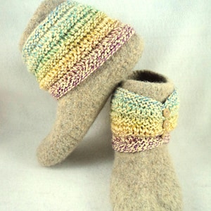 Può includere: Un paio di pantofole in lana infeltrita beige con un risvolto in maglia a coste multicolore nei toni del giallo, verde, blu e viola. La pantofola destra è decorata con tre piccoli bottoni rotondi in legno chiaro sul lato del risvolto.