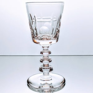 以下が含まれることがあります： カットガラスのデザインが施された、透明なガラス製の脚付きショットグラス。グラスは丸い底と、高く細長いステムを持っています。