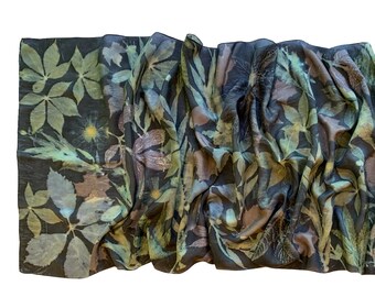 May include: A dark green silk scarf with a botanical print of leaves in shades of green, brown, and yellow.