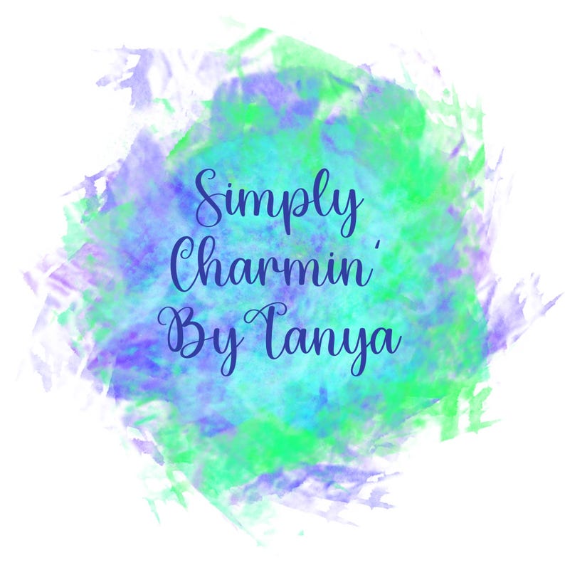 Op de afbeelding: Een aquarel-stijl ontwerp met een witte achtergrond. Het ontwerp toont een splash van groene, blauwe en paarse tinten. De tekst "Simply Charmin' By Tanya" is geschreven in een donkerblauwe, elegante scriptletter.