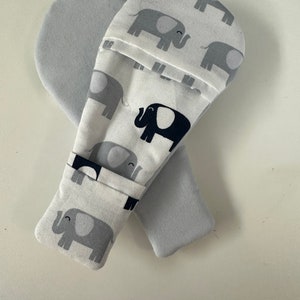 May include: A pair of gray and white fabric oven mitts with a pattern of black and gray elephants. The mitts are folded together.