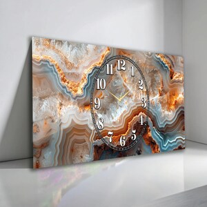 May include: Rectangular wall clock with a natural agate stone design. The clock face features black numerals and hands, set against a backdrop of brown, orange, and white patterns. The clock's design is reminiscent of a geode.