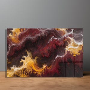 May include: Abstract art print featuring a swirling design in shades of red, yellow, and white. The artwork has a glossy finish and is displayed on a wooden surface. The piece evokes a sense of movement and energy.