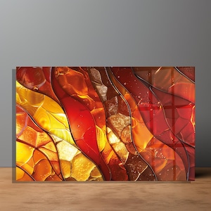 May include: Abstract artwork with a striking colour palette. The piece showcases a layered design with hues of yellow, orange, and red. It has a glossy finish and is presented on a wooden surface.