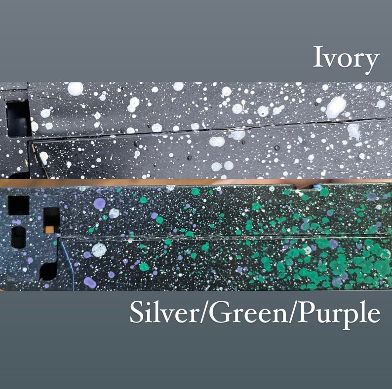 Pu&ograve; includere: Due immagini ravvicinate di una superficie nera con schizzi di vernice bianca e colorata. L'immagine superiore &egrave; etichettata "Avorio" e l'immagine inferiore &egrave; etichettata "Argento/Verde/Viola".