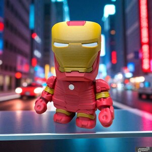 K&ouml;nnte beinhalten: Eine rot-goldene Iron Man-Figur mit einem blockartigen Design. Die Figur hat einen goldenen Helm und einen roten K&ouml;rper mit gelben Akzenten an Armen und Beinen. Der Hintergrund ist eine verschwommene Stadtszene.